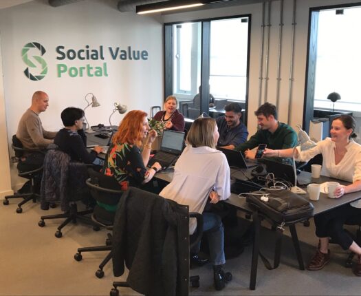 Social Value Portal staff at large table working in the office.